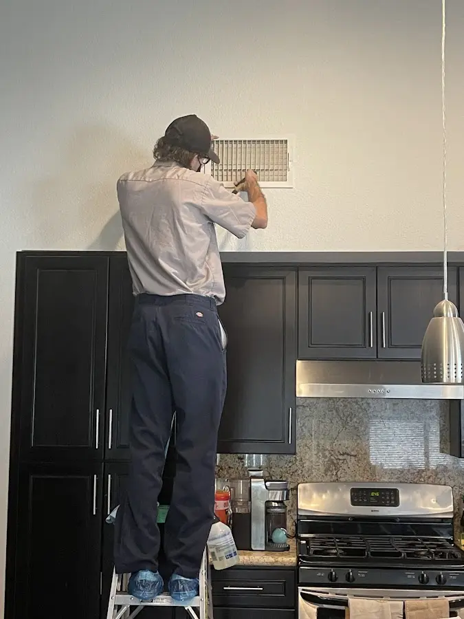 Technician inspecting an air vent during HVAC service in Seminole